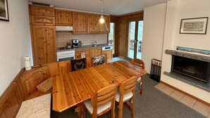 Una cucina in legno con tavolo e sedie, forno a incasso e camino.