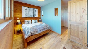 Une chambre à coucher avec un lit en bois, une grande fenêtre et une armoire en bois.