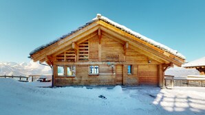 Un chalet en bois avec un toit en pente, de grandes fenêtres et une enseigne sur laquelle on peut lire « Chalet Egli ».