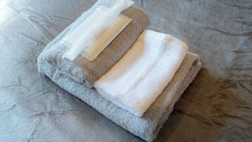 A neatly folded gray towel with a transparent plastic bag on a textured fabric surface.