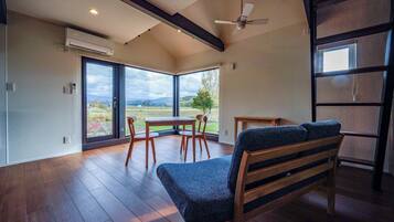 Enjoy a spacious room with a high ceiling, sliding glass door, and scenic outdoor view.