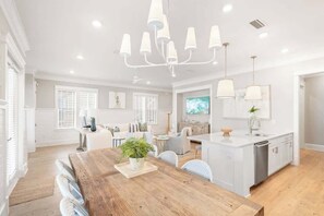 A spacious kitchen with a central island, pendant lighting, and a dining area with a wooden table. - Hola Beaches by Stay on 30a (Inlet Beach)