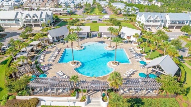 Um resort com piscina central, áreas de estar e vista para o oceano.