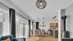 Ein modernes Wohnzimmer mit Sofa, Essbereich, Küche und großen Fenstern.