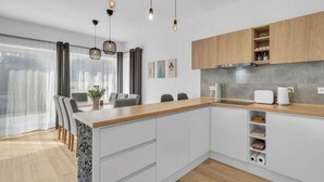 Eine moderne Küche mit weißen Schränken, einer Holz Arbeitsplatte und Pendelleuchten.