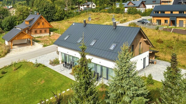 Ein modernes Haus mit Satteldach, großen Fenstern und einem gepflegten Rasen.