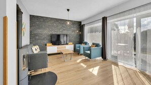 Ein modernes Wohnzimmer mit Kamin, Fernseher und großem Fenster.