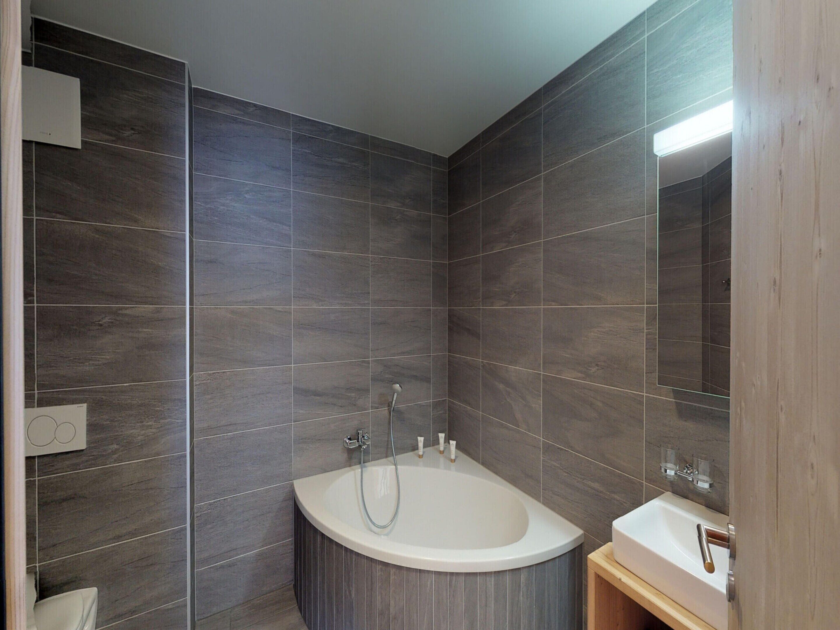 Une salle de bain moderne avec une baignoire sur pieds, un meuble-lavabo en bois et un grand miroir.