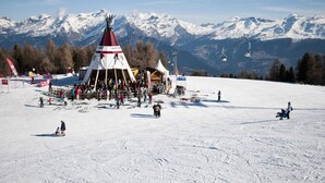 A ski resort with a prominent ski lift and a large gathering of people near a red and white tent structure. - Exquisite Apartment With Balcony (Veysonnaz)