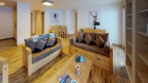 A modern living room with two wooden sofas, a coffee table, and a dining area with wooden chairs. - Exquisite Apartment With Balcony (Veysonnaz)