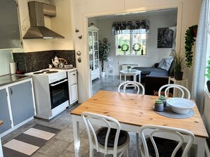 A modern kitchen with a stove, oven, and white cabinets. There is a dining table with chairs and a small side table. - 4 Person Holiday Home in Farjestaden (Farjestaden)