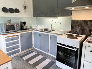 A modern kitchen with grey cabinets, a white stove, and a microwave. - 4 Person Holiday Home in Farjestaden (Farjestaden)