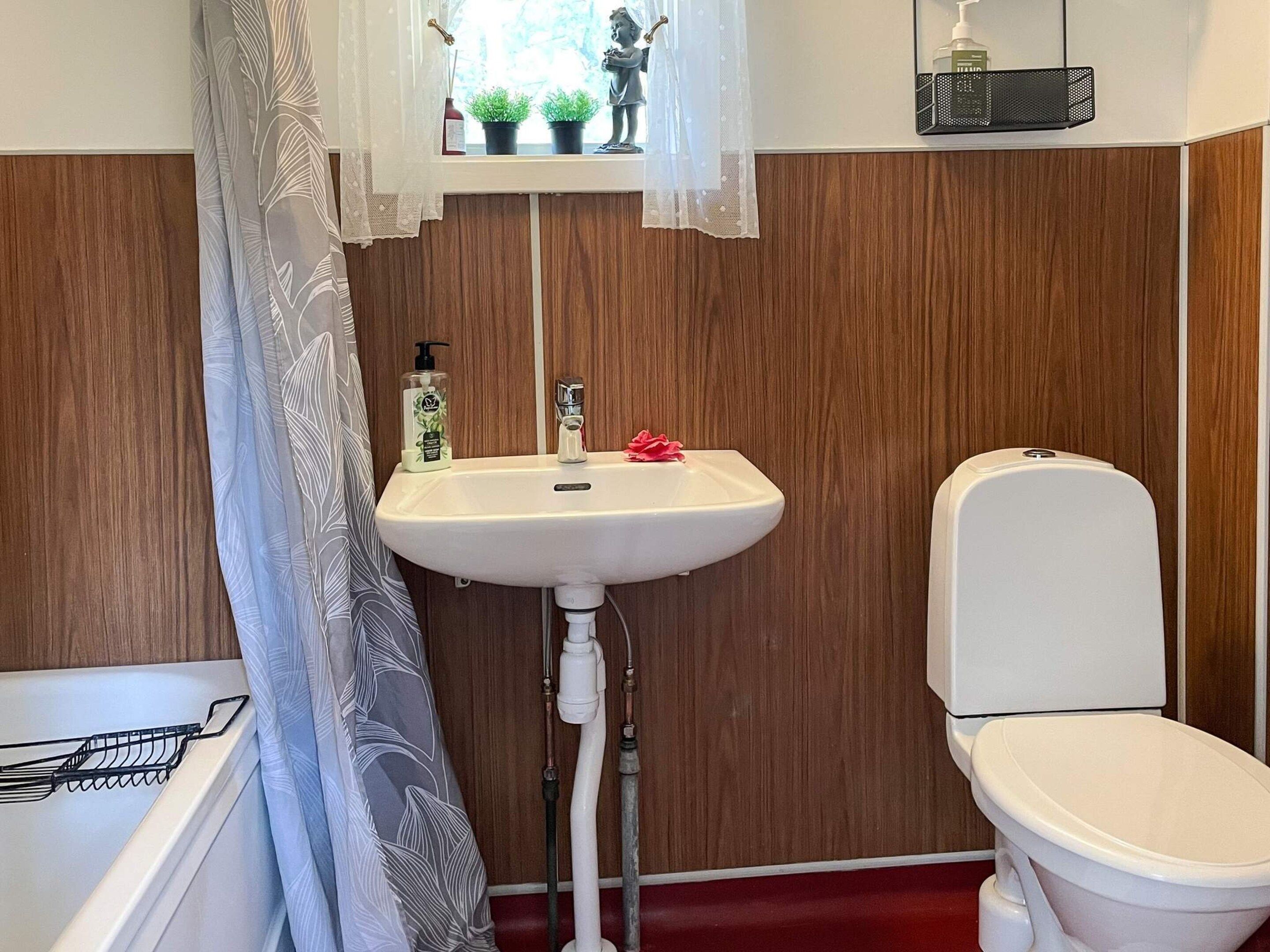 A bathroom with a white sink, a toilet, and a shower area.