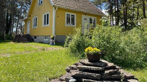 A yellow wooden house with a tiled roof, surrounded by greenery and trees. - 4 Person Holiday Home in Farjestaden (Farjestaden)