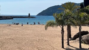 Une plage de sable avec des palmiers et un phare en arrière-plan.