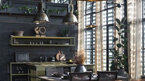 A modern kitchen with pendant lighting, a dining area with a table and chairs, and a large window with curtains. - The Bohemian Bali, a Member of Design Hotels (Canggu)