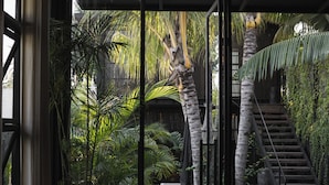 A modern interior with a wooden staircase, a seating area, and lush greenery. - The Bohemian Bali, a Member of Design Hotels (Canggu)