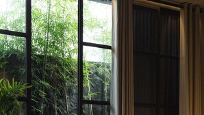 A bedroom with a large window, a bed, a chair, and a carpet. - The Bohemian Bali, a Member of Design Hotels (Canggu)