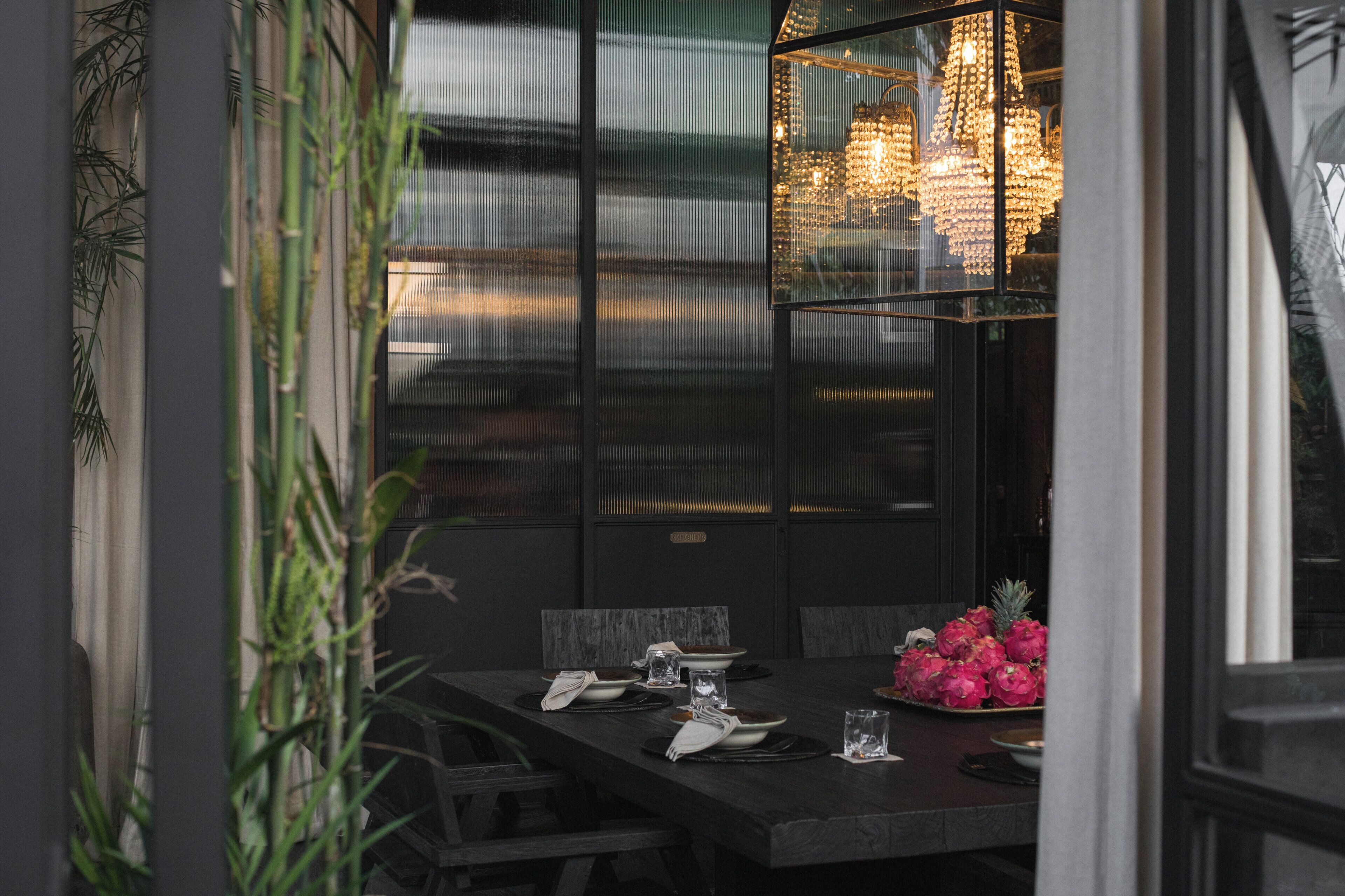 Une table à manger dressée avec des assiettes, des verres et un centre de table composé de fleurs.