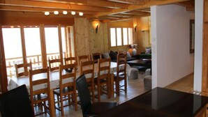 Un intérieur en bois comprenant un espace repas, un bar et un coin salon avec vue.