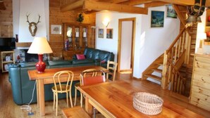 Un intérieur rustique avec des éléments en bois, notamment une table à manger en bois, des chaises, un canapé et un escalier.