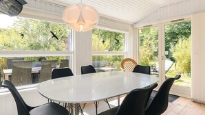 A sunroom with a round table and chairs, large windows, and a hanging light fixture. - 6 Person Holiday Home in Borup (Borup)