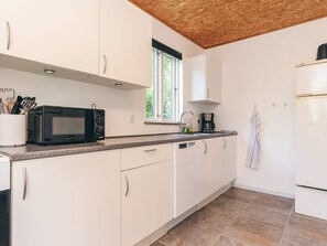 A modern kitchen with white cabinets, a microwave, a coffee maker, and a window. - 6 Person Holiday Home in Borup (Borup)