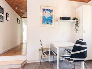 A dining area with a white table, two chairs, a framed artwork, and a radio on a shelf. - 6 Person Holiday Home in Borup (Borup)
