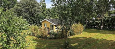 Una casa petita i groga envoltada d'arbres i gespa.
