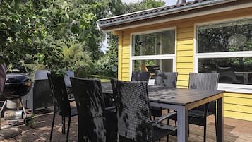Un edificio amarillo con una terraza, asientos al aire libre y una parrilla.