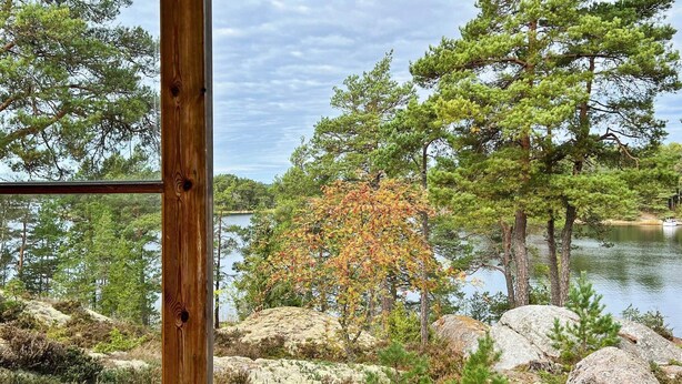 Une terrasse en bois donnant sur un lac, avec des arbres et des rochers.
