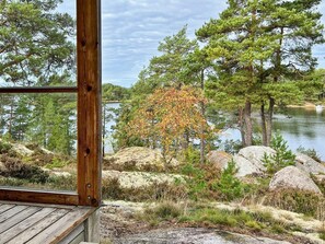 Eine Holzterrasse mit Blick auf einen See, Bäume und Felsen.