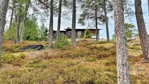 Une cabane située dans une zone boisée, dotée d’une terrasse en bois et offrant une vue sur les arbres environnants.