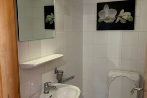 Ein Badezimmer mit einem weißen Waschbecken, einem Spiegel, einer Toilette und zwei Orchideenbildern an der Wand.