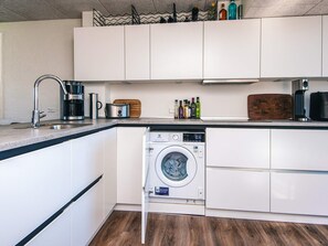 A compact kitchen with a built-in washing machine, a coffee maker, and a toaster.
