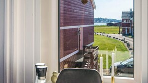 Een kamer met een groot raam met uitzicht op een rode gebouw en een grasveld.
