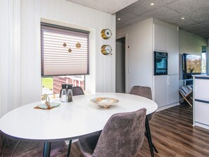A dining area with a round table, chairs, and a window with blinds.