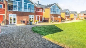 Een rij moderne huizen met grote ramen, een grindpad en een gazon.