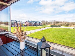 A view from a window overlooking a green lawn and a row of houses. - 4 Person Holiday Home in Lemvig (Lemvig)