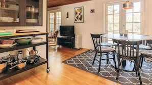 A modern kitchen with a wooden ceiling, a dining area with a round table and chairs, and a TV in the background. - 6 Person Holiday Home in Rodby (Rodby)