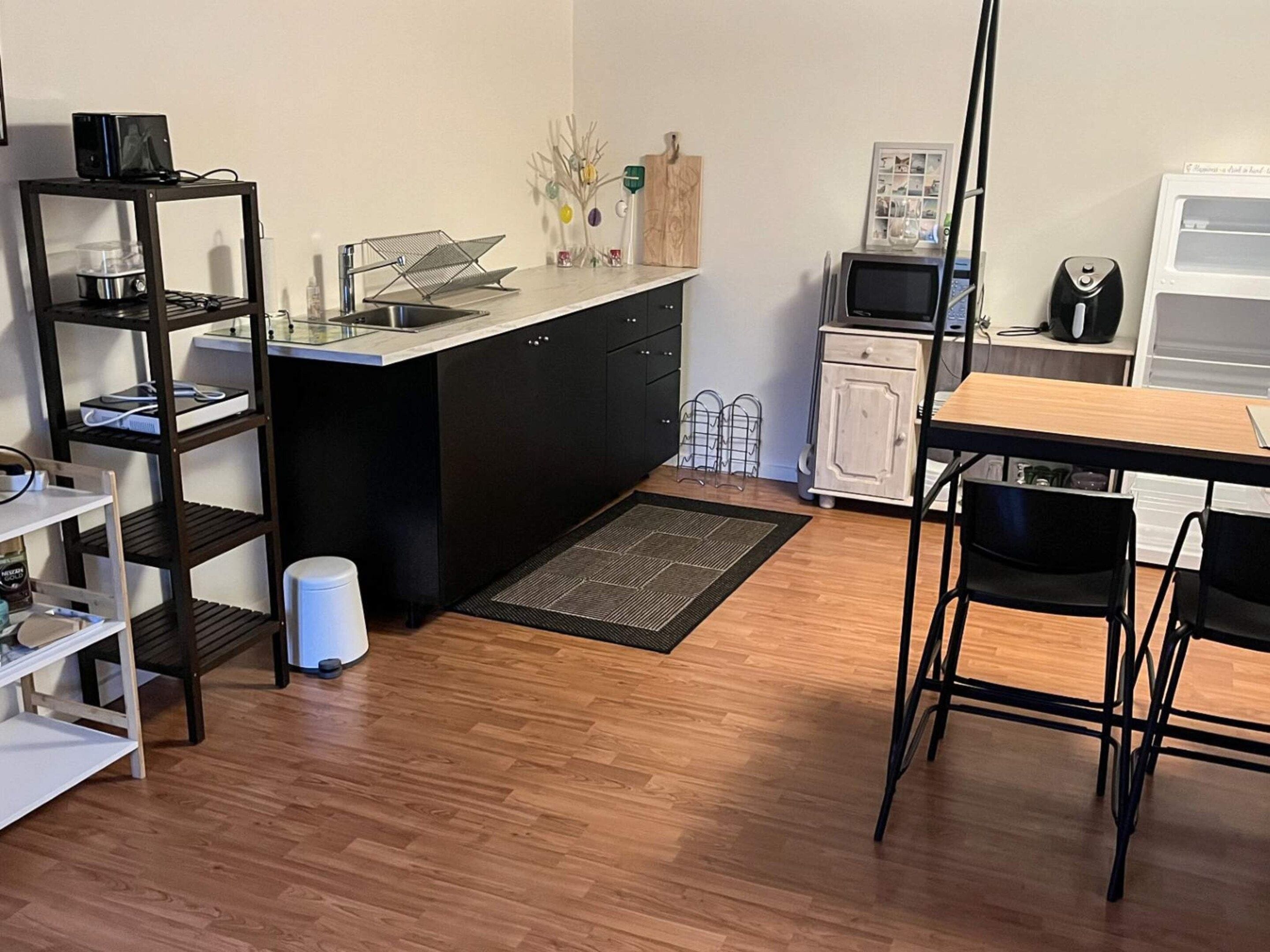Cocina compacta con isla central, microondas, refrigerador pequeño y comedor con mesa y sillas.