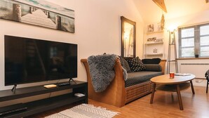 A modern living room with a large flat-screen TV, a wooden sofa, a small round table, and a decorative rug. - 5 Person Holiday Home in Saeby (Sæby)