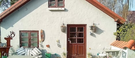 A house with a brown door, a window with shutters, and a small porch area.