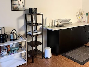 A compact kitchen with a white countertop, a black cabinet, a white trash bin, and a black and white shelf unit. - 5 Person Holiday Home in Saeby (Sæby)