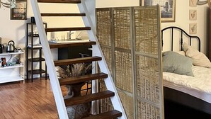 A bedroom with a bed, a nightstand, a dresser, a window, and a staircase. - 5 Person Holiday Home in Saeby (Sæby)