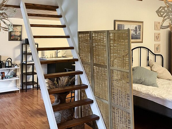 A bedroom with a bed, a nightstand, a dresser, a window, and a staircase. - 5 Person Holiday Home in Saeby (Sæby)