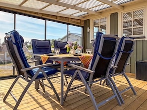 A covered patio with a table and chairs, large windows, and a view of the neighborhood. - 5 Person Holiday Home in Falkenberg (Falkenberg)