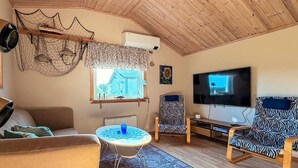 Ein Wohnzimmer mit einer Couch, einem gemusterten Sessel, einem Fernseher und einem Deckenventilator.