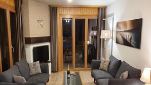 Ein Wohnzimmer mit zwei Sofas, einem Couchtisch, einem Fernseher und einem Gemälde an der Wand.