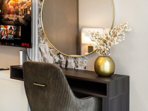 A modern room with a television displaying a show, a round mirror, a vase with dried flowers, and a dark-colored chair. - New 1BR | Burj Khalifa Infinity Pool | Dubai Mall (Dubai)